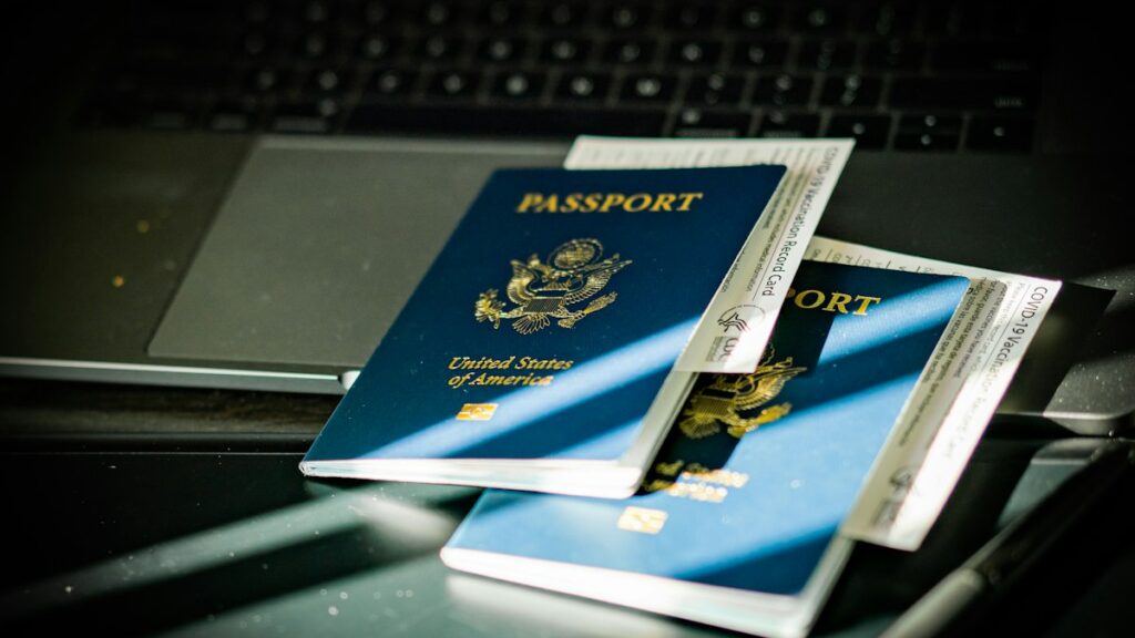 Passport on a laptop keyboard while checking how to verify a migration agent